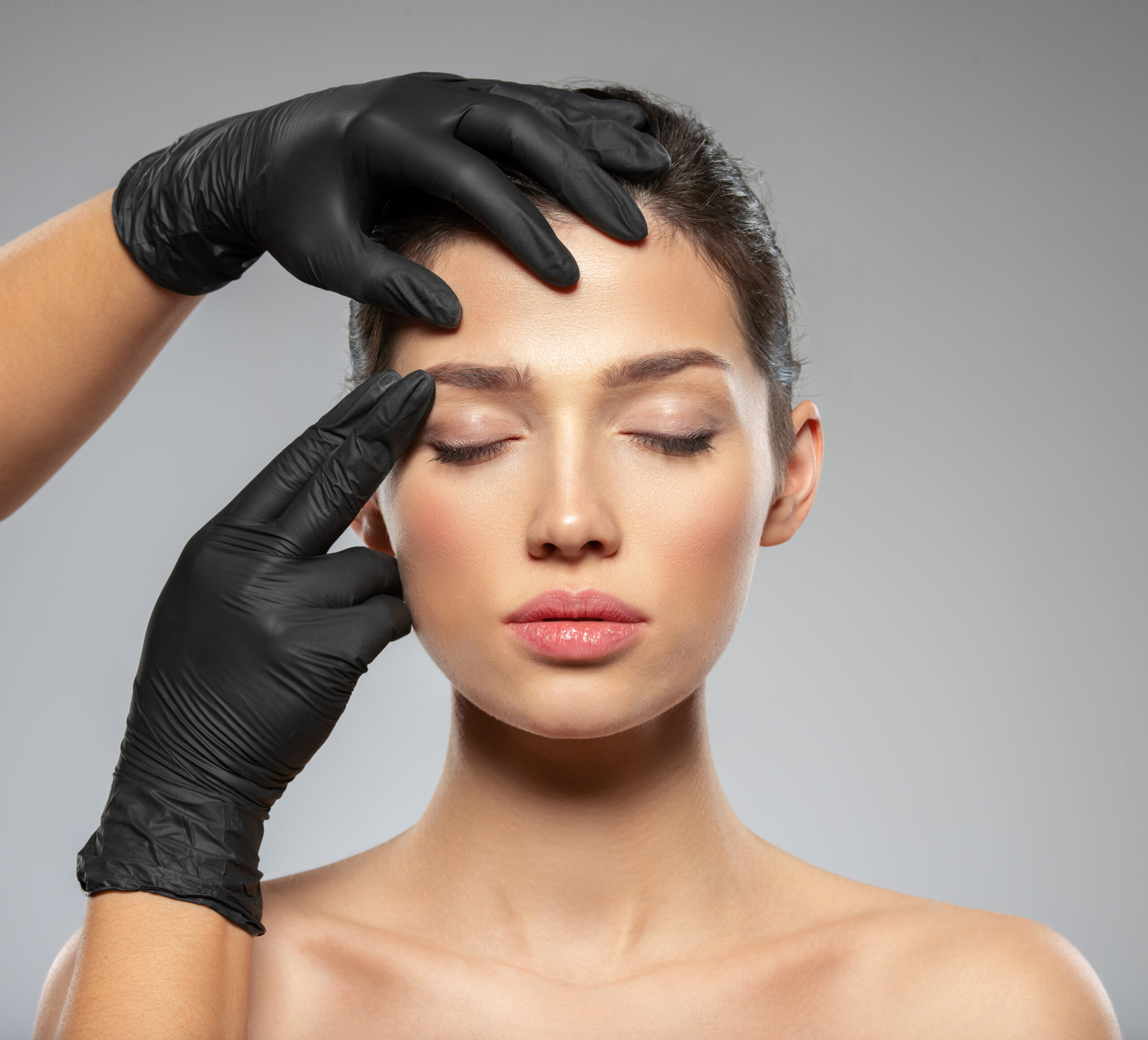 Face skin check before plastic surgery. Beautician touching woman face. Doctor checks a skin before plastic surgery. Beauty treatments. Plastic surgery doctor is touching face of a patient by hands